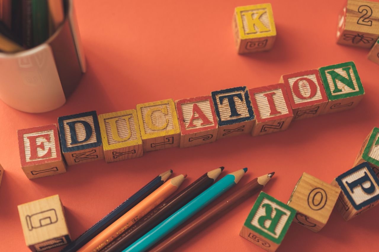About Alphabet blocks spelling 'EDUCATION' on orange background with pencils.