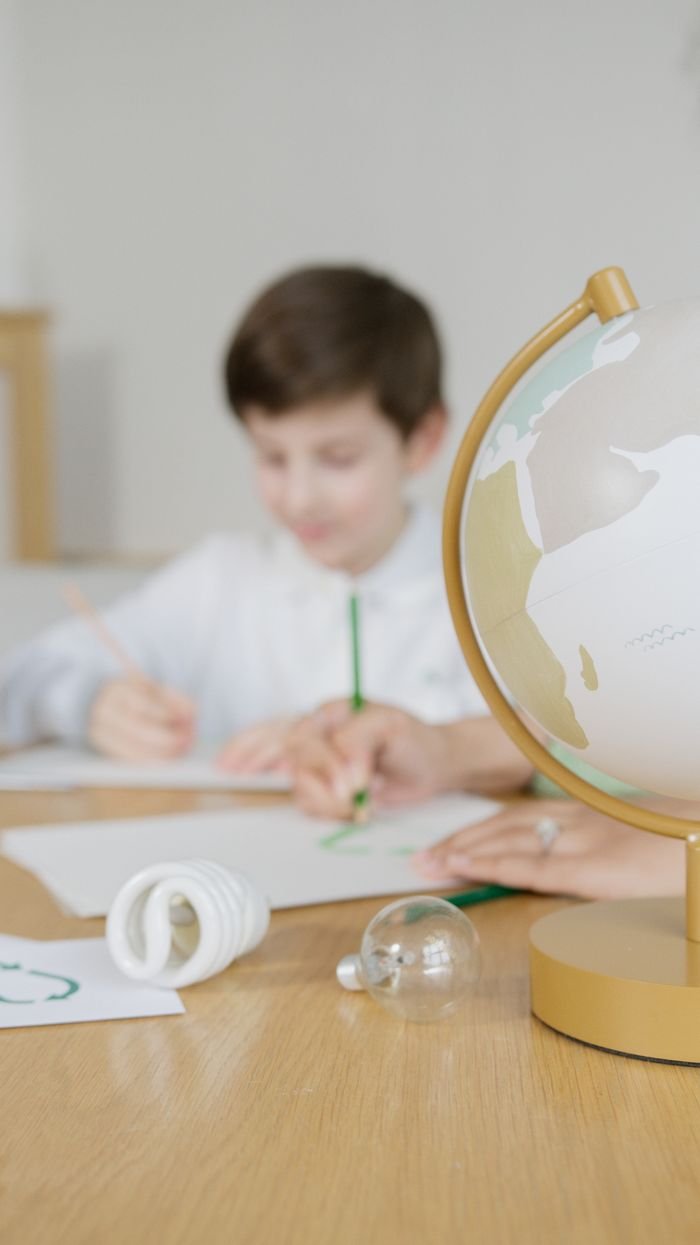 The Art of Drawing Readers In: Your attractive post title goes here A child studies with a globe, emphasizing education and sustainability themes.