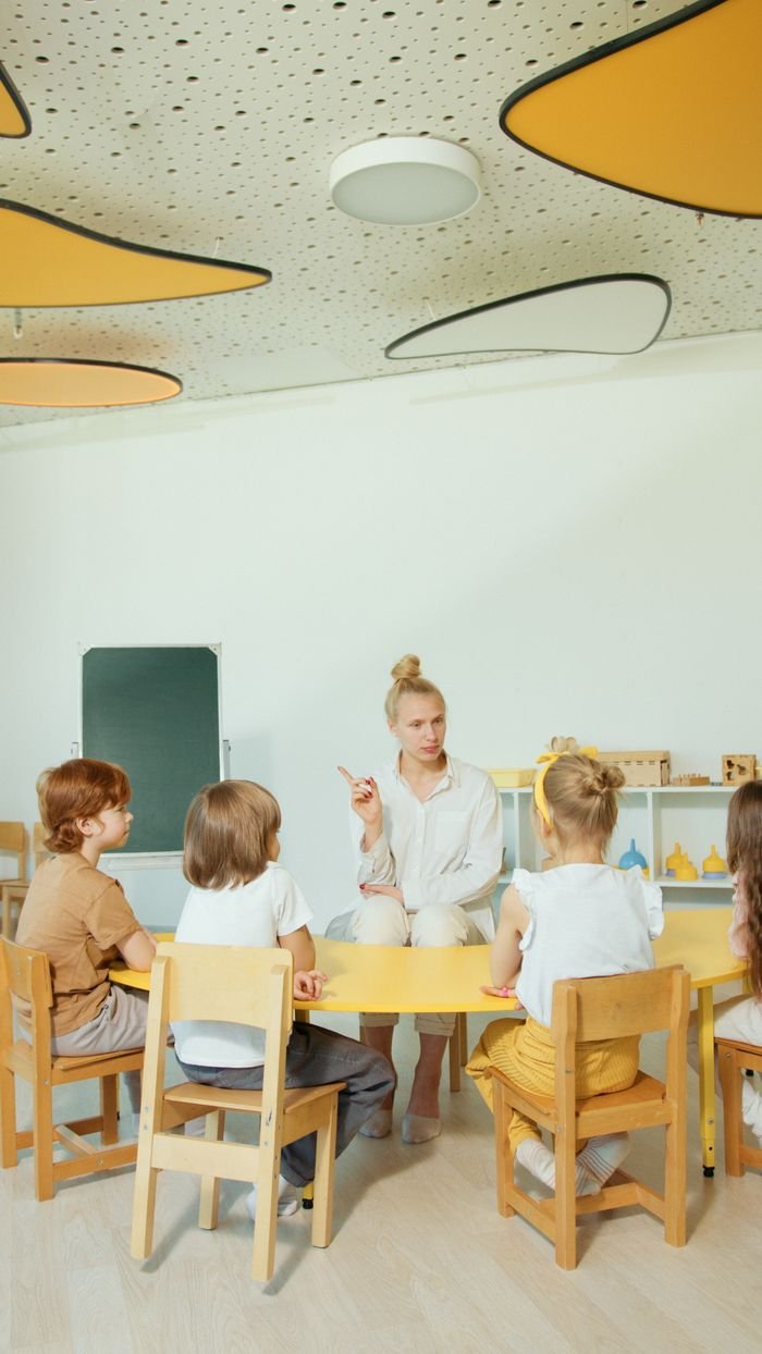 Services Children gathered around a teacher in a vibrant, modern classroom setting.