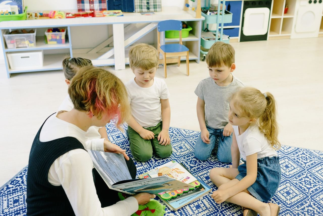 Mastering the First Impression: Your intriguing post title goes here Group of children and a teacher reading together indoors at preschool.